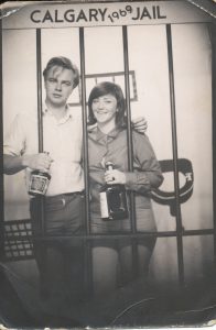 young man and women both holding liquor bottles and behind mock prison cell bars