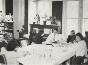 Photo en noir et blanc d'un groupe d'hommes et de femmes réunis autour d'une table