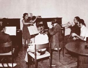 Photo en noir et blanc d'un groupe d'hommes et de femmes jouant divers instruments de musique