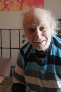 Older man smiling with white hair and beard