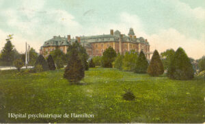 Imposant édifice ancien, en brique, au sommet d'une colline avec des arbustes et de l'herbe en face