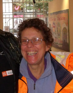 smiling middle-aged woman with glasses and short curly hair