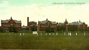 old coloured photograph of series of larger old brick residential buildings, field and cricket game in front