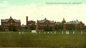 Ancienne photographie en couleurs représentants une série d'immeubles anciens en brique et des hommes jouant au cricket devant