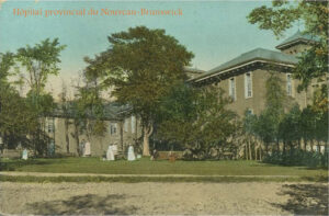 Ancienne photo en couleurs représentant un vieil édifice institutionnel en pierre entouré d'arbres avec des femmes en longues robes blanches sur le terrain devant