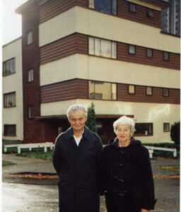 man and woman standing in front of an older apartment building
