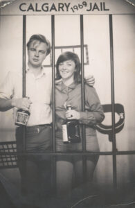 young man and woman holding bottle of alchol in fake jail