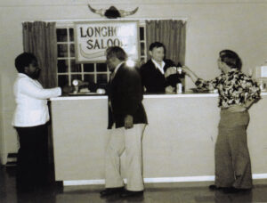 Man behind counter serving drinks and 3 men in front of counter.