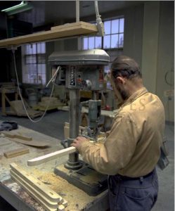 Homme debout devant une table d’un atelier industriel, travaillant sur un projet