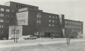 Ancienne photo en noir et blanc d'un grand hôpital avec des voitures stationnées devant