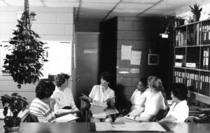 Photographie en noir et blanc des années 1970 représentant un groupe des employés de bureau en réunion