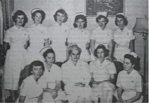 group of nurses wearing uniforms and caps, circa 1950s