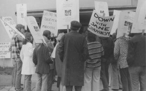 small crowd of 1970s protesters with signs