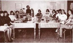 Photo en noir et blanc d'un groupe d'hommes et de femmes réuni autour d'une grande table