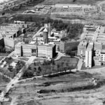 Photo en noir et blanc d'une vue aérienne d'un vaste complexe composé de plusieurs bâtiments institutionnels