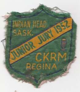 small green badge with torn edges and yellow text reading Junior Jury 1952
