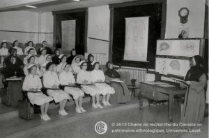 Photo en noir et blanc représentant une religieuse s'adressant à une classe composée de femmes en tenue d'infirmière et de femmes en tenue de religieuse