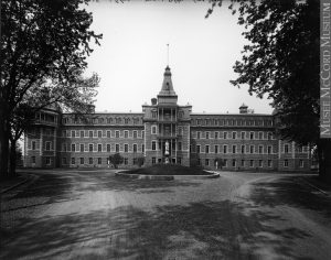 Four-storey building of gray stone surrounded by trees