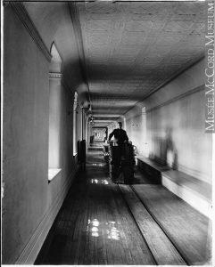 Long corridor étroit au centre duquel il y a un wagon de train électrique conduit par un homme