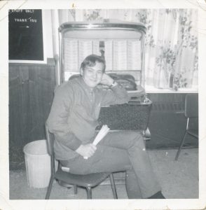 young man sitting on chair in front of a jukebox