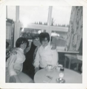 3 young people sitting at cafeteria table with coffee cups