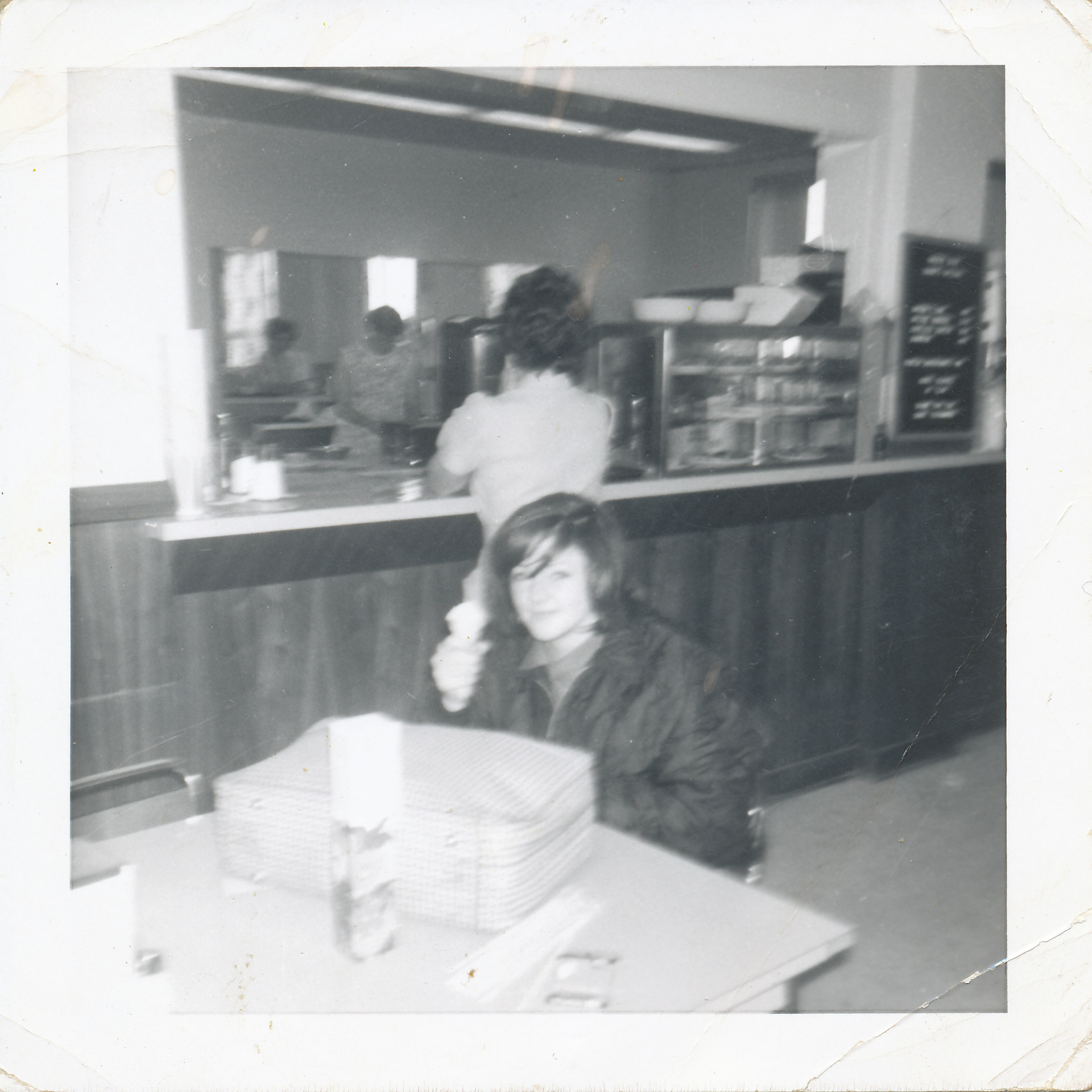 young woman sitting at table in cafeteria with serving counter behind