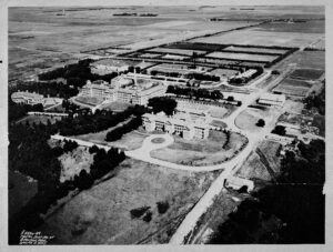 aerial photography of large asylum complex showing old brick main building, roads, outbuilding and farming area