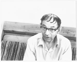 man with dark hair and glasses sitting on couch