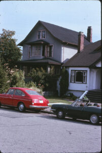 old house and front garden with cars parked in front