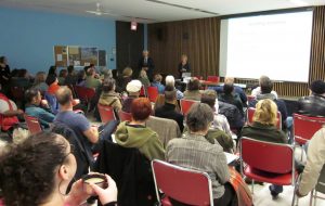 crowd in room listening to man and woman speak