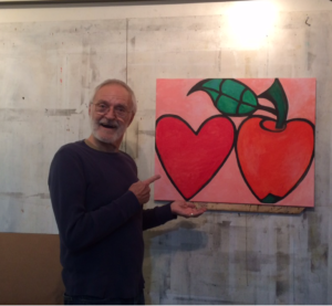 person holding painting of a red apple and a red heart