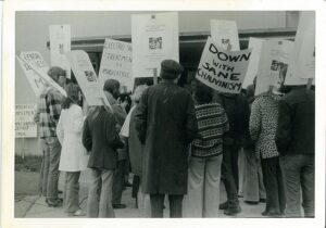 group of 1970s people protesting holding signs with slogans