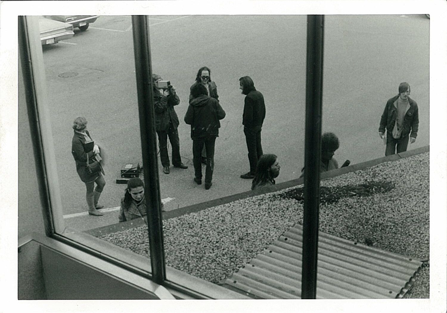 6 people viewed from a window above standing on sidewalk